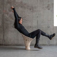 Student sitting on the prototype of a piece of furniture.